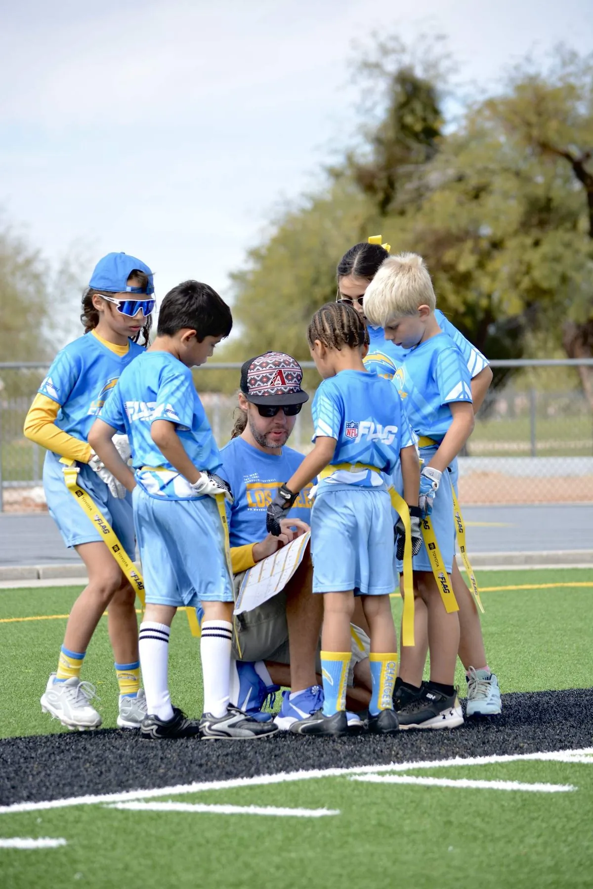 Coach kneeling in the huddle walking the team through the play card